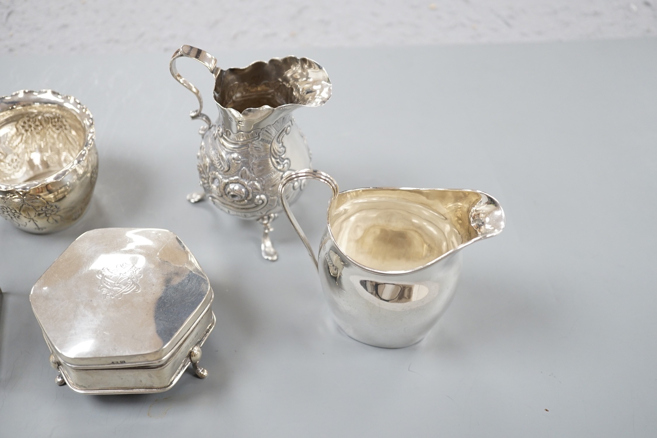 An Edwardian repousse silver bachelors cream jug and sugar bowl, Birmingham, 1904, two other late 19th/early 20th century silver cream jugs, a silver five bar toastrack and a silver mounted trinket box.